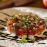 Bowl of flavorful Bruschetta Dip served with fresh bread and vegetables.