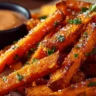 Crispy oven baked sweet potato fries served on a plate with dipping sauce.