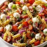 Delicious cold pasta salad in a bowl with fresh vegetables and dressing