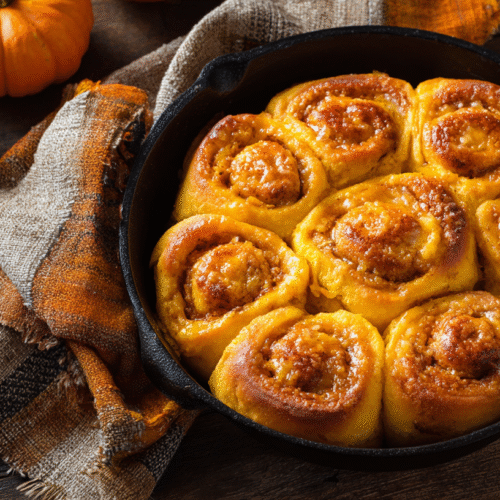 Freshly baked pumpkin pan rolls served on a plate.