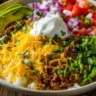 A colorful Taco Rice Bowl topped with seasoned beef, fresh veggies, and salsa.