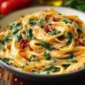 Vegan creamy sun dried tomato pasta served in a bowl with fresh basil and garlic.