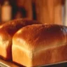 Freshly baked Amish White Bread loaf on a wooden cutting board