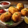 Golden baked arancini served on a plate with marinara sauce