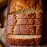 A slice of freshly baked moist banana bread on a wooden table.