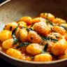 Creamy pumpkin gnocchi dish topped with herbs and parmesan cheese