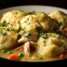 A bowl of delicious Crockpot Chicken and Dumplings with fresh herbs