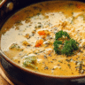 Bowl of creamy vegetable soup with fresh vegetables and herbs