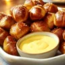 A plate of freshly baked pretzel bites with dipping sauces.