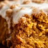 Slice of pumpkin coffee cake on a plate, topped with cream cheese frosting.