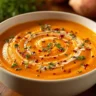 A bowl of creamy roasted sweet potato soup garnished with herbs