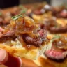 Delicious Steak Crostini garnished with creamy horseradish sauce and caramelized onions