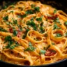Creamy vegan sun-dried tomato pasta served in a bowl with fresh herbs